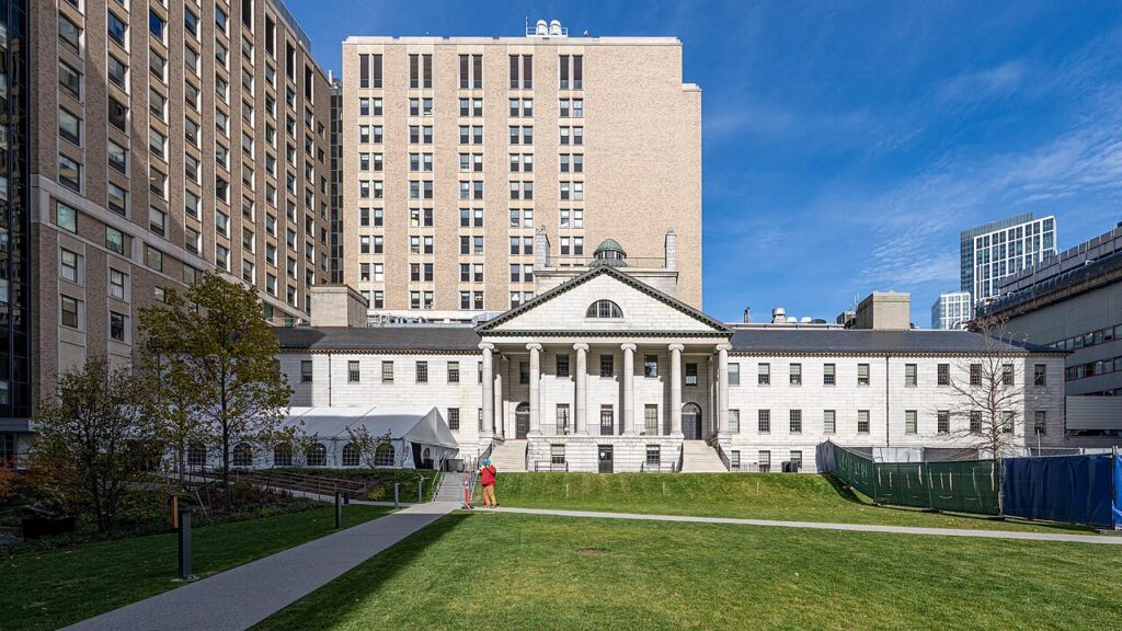 The granite Bulfinch Building at Massachusetts General Hospital in Boston, with its columned portico and dome above a green lawn on a sunny day