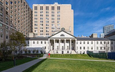 The granite Bulfinch Building at Massachusetts General Hospital in Boston, with its columned portico and dome above a green lawn on a sunny day