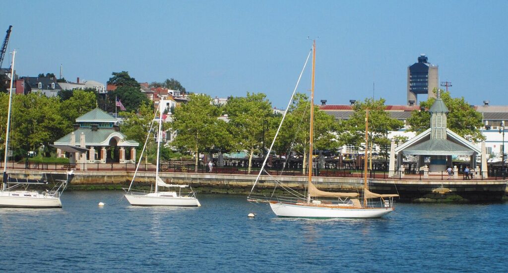 Sailboats moored off the Piers Park waterfront promenade and pavilions along the East Boston Harborwalk on a sunny day