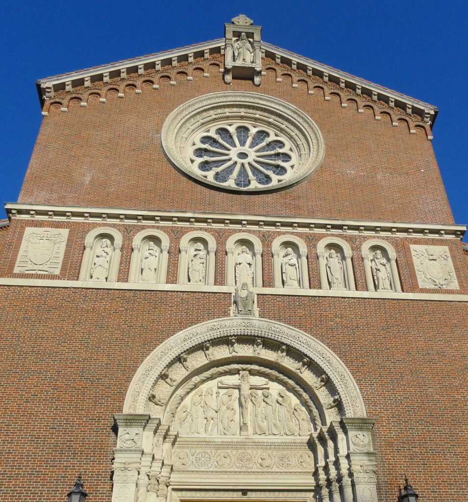 The rose window and carved facade of Holy Name Church in West Roxbury under a deep blue sky